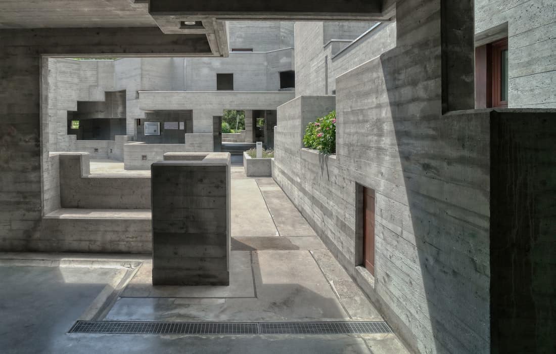 Layered concrete volumes receding into a covered interior.